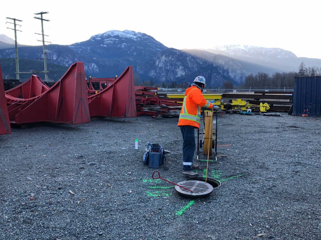 Technician feeds duct rodder down a manhole